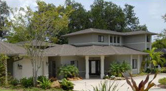 two-story house with lots of green trees and bushes around it